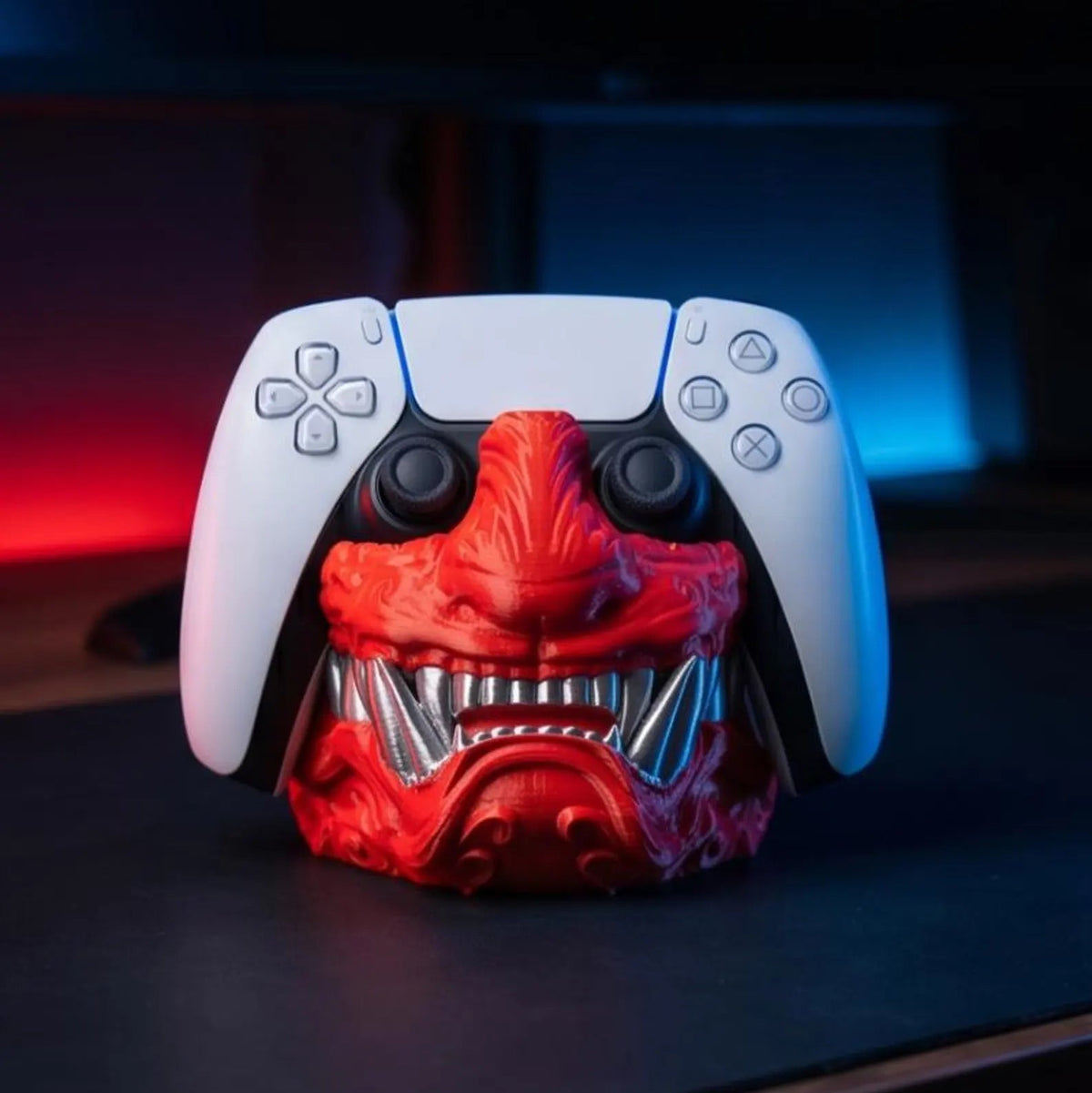 Samurai Oni Controller Stand with red mask and silver-tone teeth holding a PS5 DualSense controller, front view